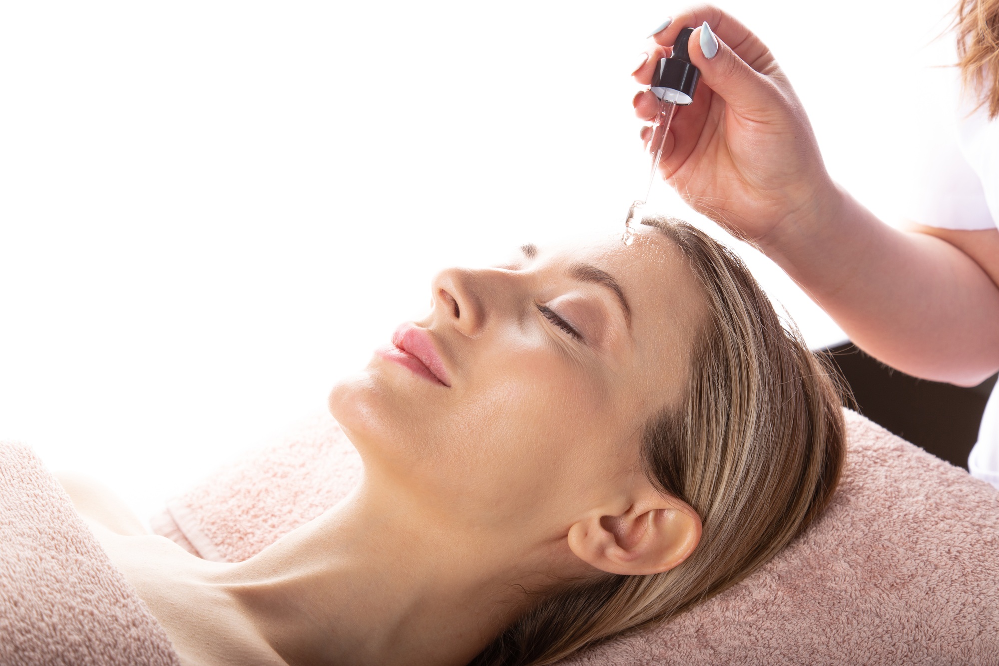 Beauty expert performing serum application for skin care.