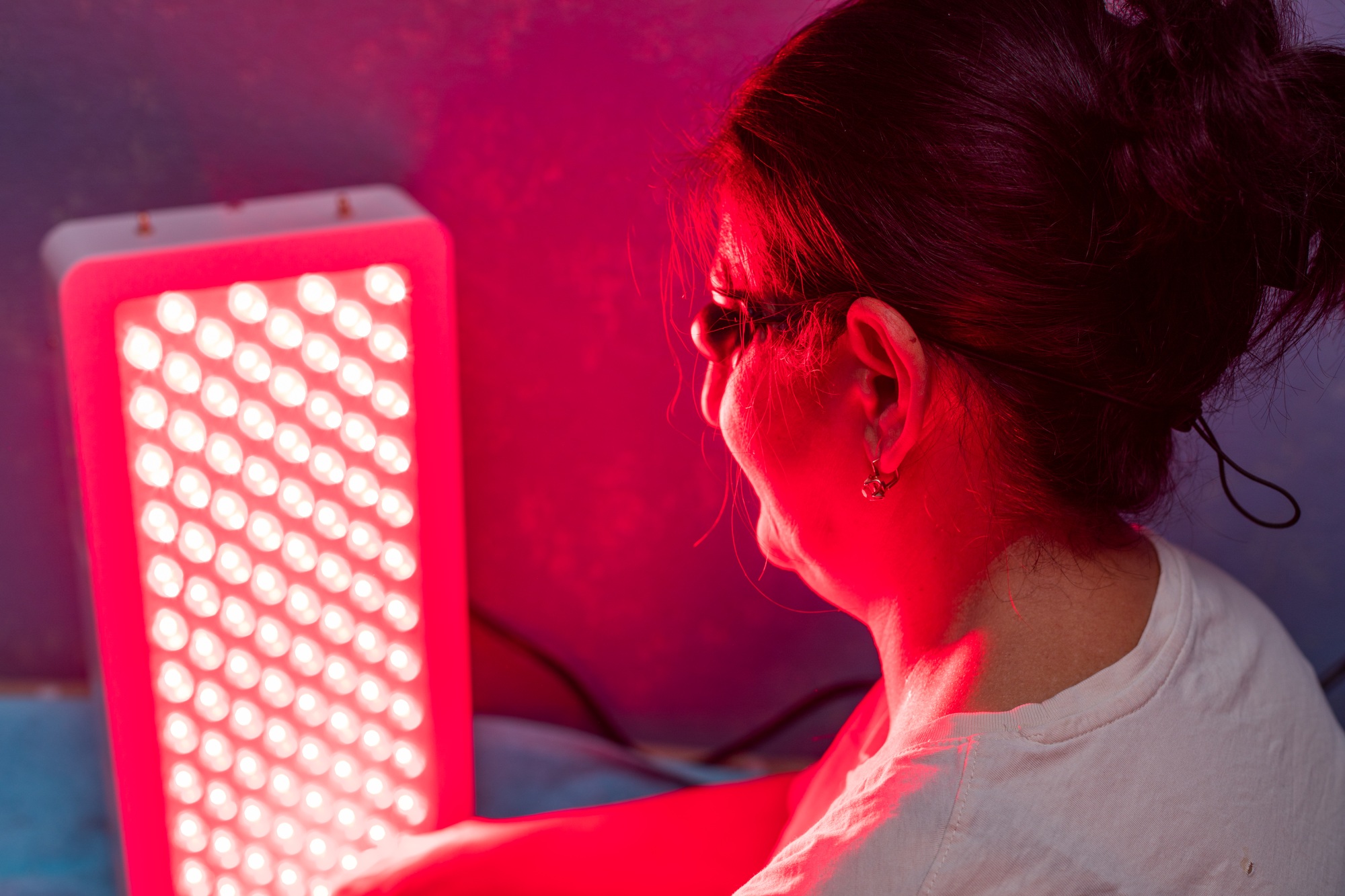 Senior Woman doing the Red Light Therapy Session with Panel at home