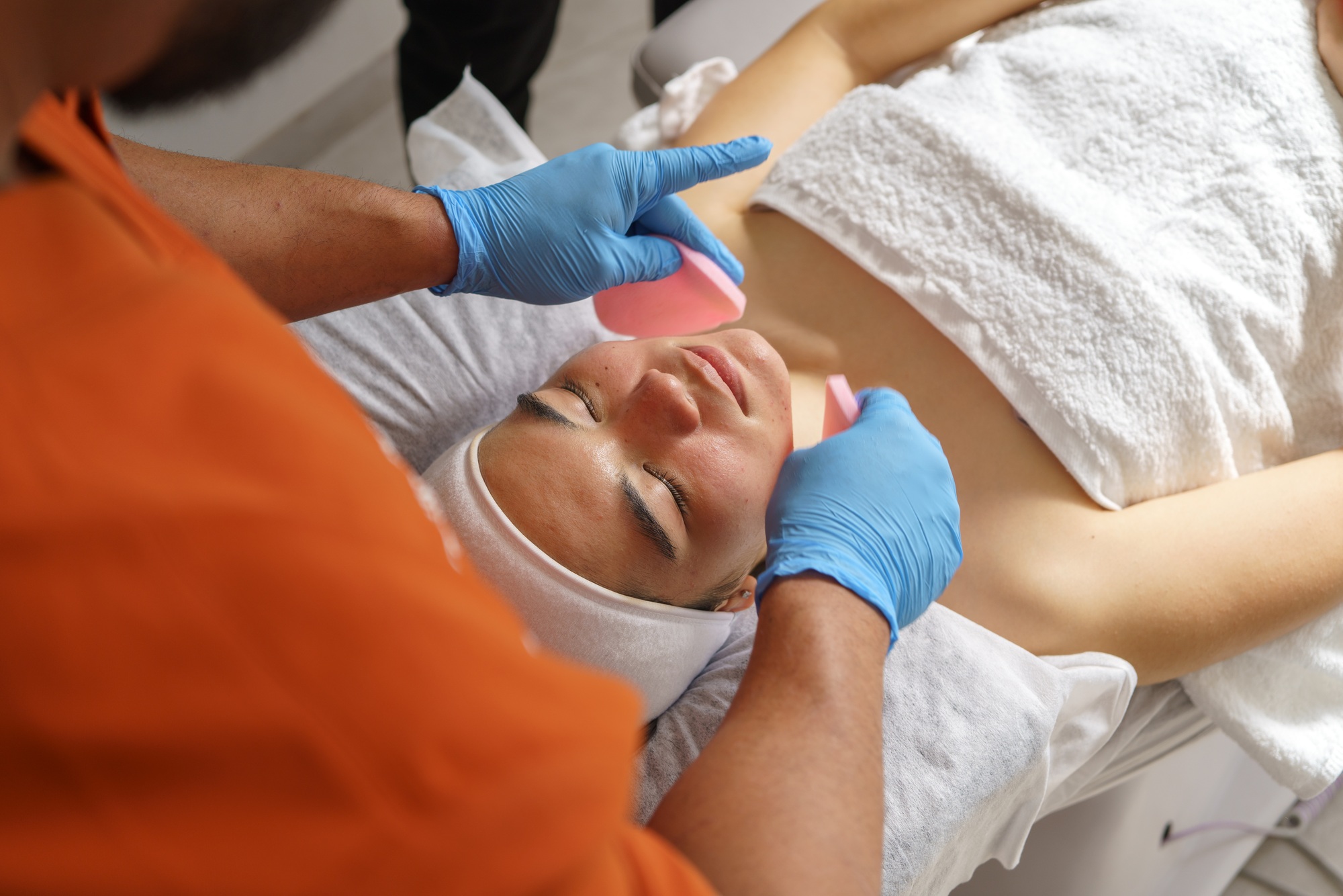Skincare professional wearing blue gloves performing chemical peel treatment